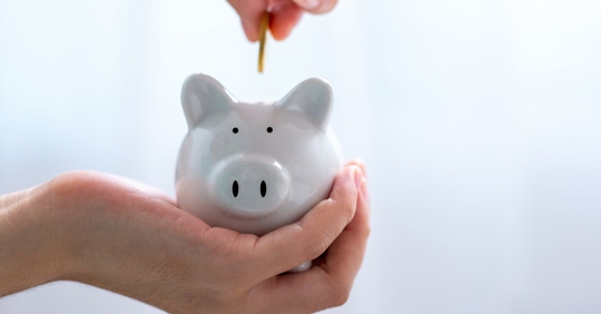 man putting money in piggy bank